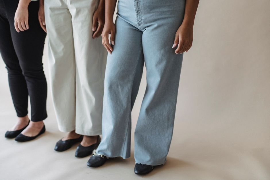 Flat lay of wide leg jeans styled with statement belt, structured handbag, layered jewelry, and polished shoes for accessorizing ideas