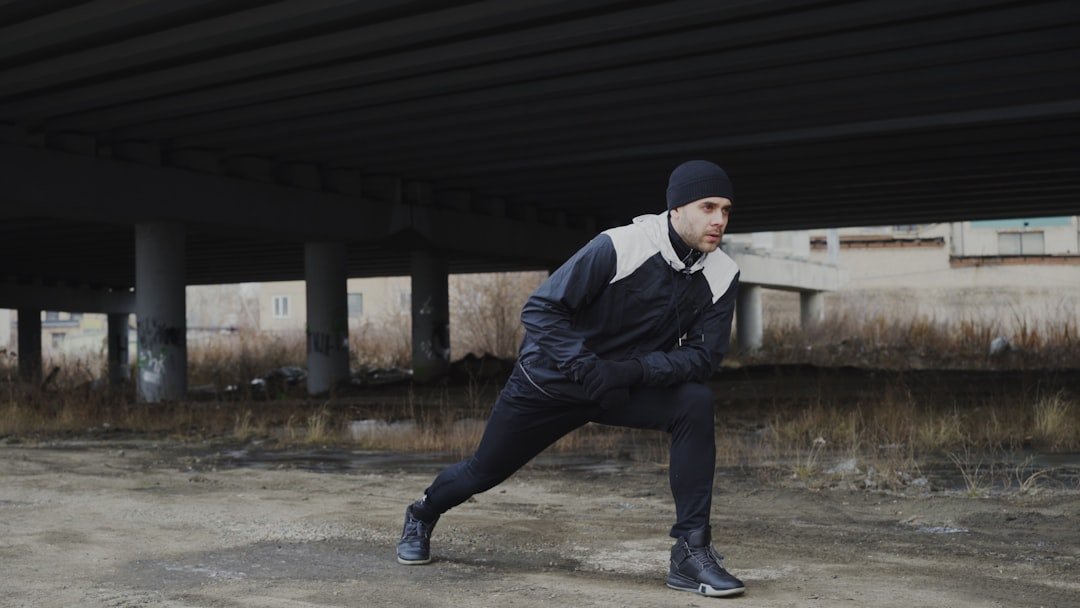 Street style outfit featuring gray sweatpants with a long coat, sneakers, crossbody bag, and beanie for a chic winter look