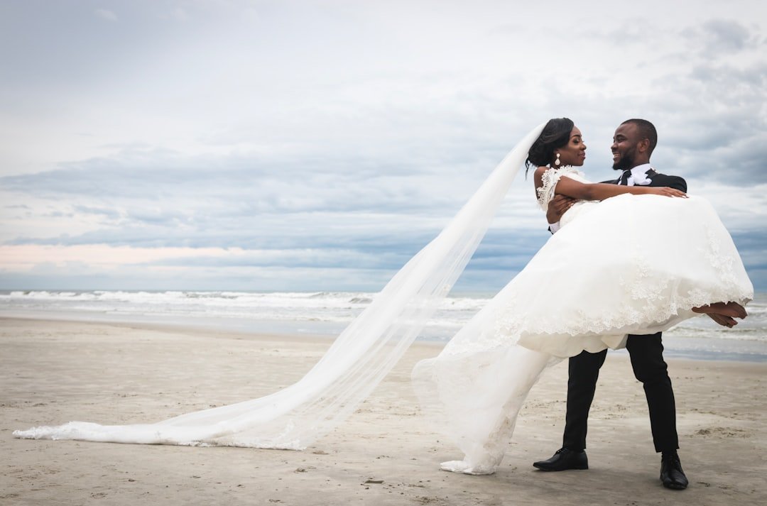 Plus size woman in turquoise maxi dress at beach wedding holding sunhat