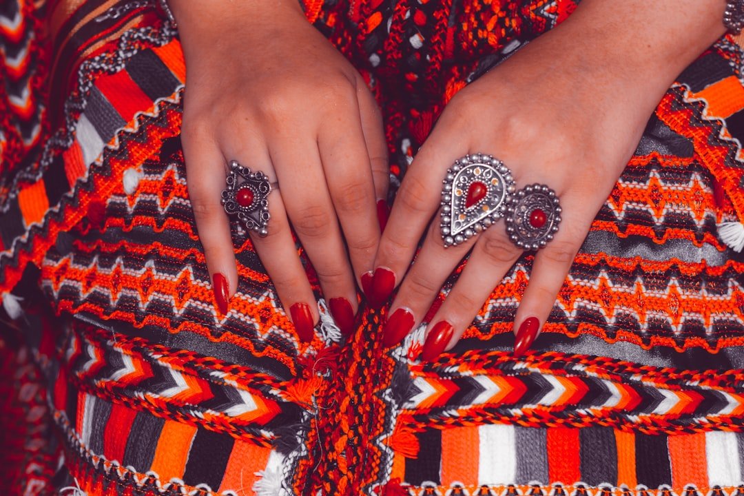 Neon orange nails with glow-in-the-dark effects and rhinestone accents styled for festival season