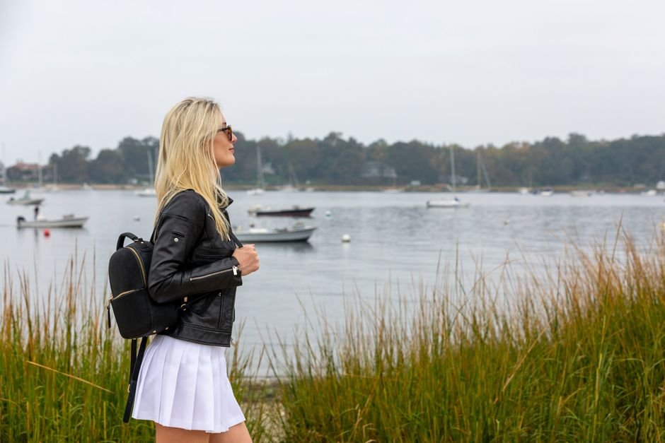 Clothing rack with blazers, pleated skirts, loafers, and sweaters as essential pieces for preppy fall outfits.