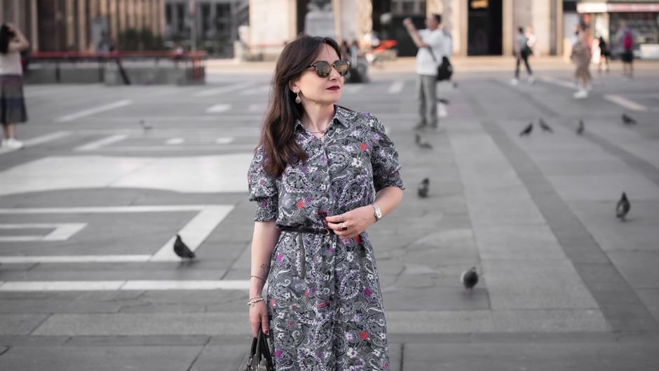 Model wearing a printed midi dress with artisanal embroidery and pearl-embellished handbag, showcasing Italian summer outfit trends 2025.