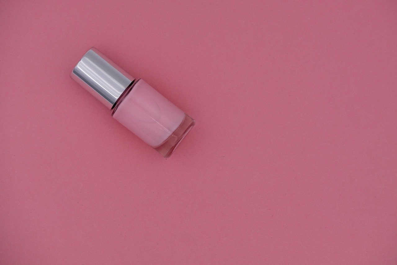 Nail care essentials for maintaining seashell nail designs, including cuticle oil and top coat.