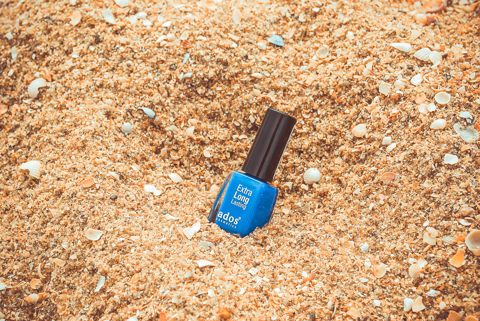 Hands applying clear top coat over vibrant summer nails to extend polish longevity