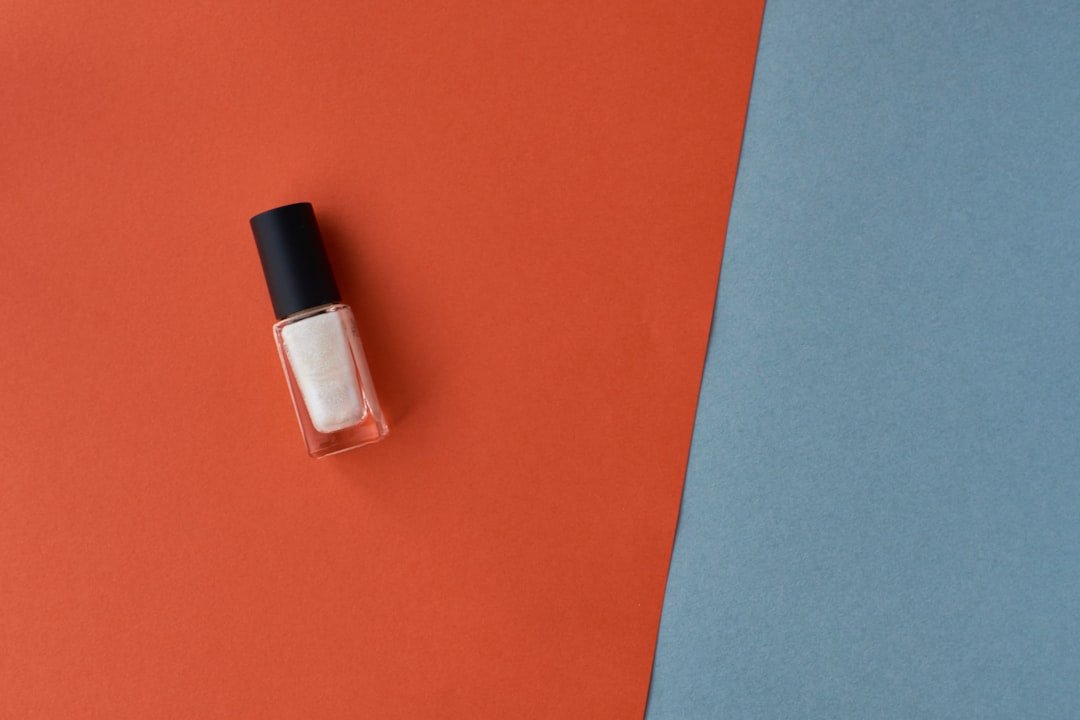 Flat-lay of orange nail polish, nail art brushes, and autumn-themed decals shopping guide for fall nail essentials