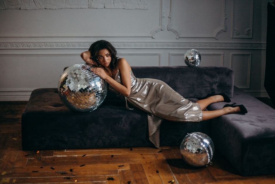 Woman styled in retro glam dress with pearls, vintage curls, and clutch bag, showing how to accessorize vintage-inspired outfits